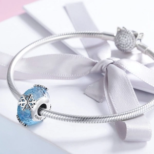 Detailaufnahme des S925 Silber-Charm-Armbands mit blauer Schneeflocke und Katzenperle
