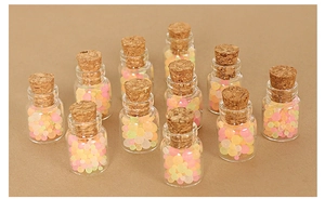 Close-up of 12 miniature glass jars with cork stoppers and colorful candy-like beads