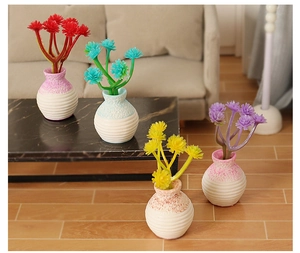 Miniature dollhouse flower pots set with colorful blossoms on marble coffee table