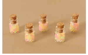 Macro detail of five miniature glass jars with natural cork stoppers and colorful resin beads