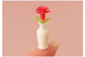 Miniature dollhouse flower vase shown on fingertip to highlight ultra-small scale