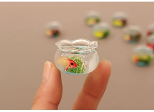 Macro detail of miniature dollhouse fish tank with tiny resin goldfish and aquatic plants