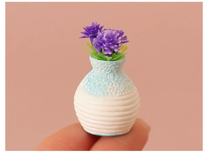 Macro shot of miniature blue and white vase with purple flowers held on a fingertip