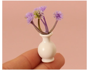 Macro detail of a miniature white ceramic vase with purple flowers held by a fingertip