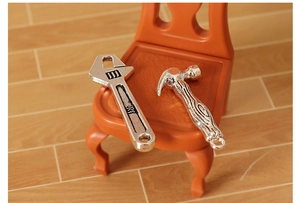 Macro detail of alloy miniature wrench and claw hammer tools on a tiny orange chair