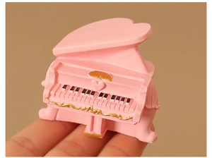 Vista macro de un piano miniatura rosa en forma de corazón con relieves dorados