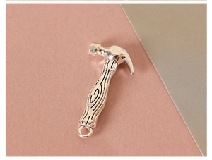 Detailed view of mini silver metal hammer pendant with realistic wood texture handle