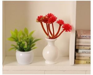Detailed macro view of miniature dollhouse red flowers in a white vase on a bookshelf