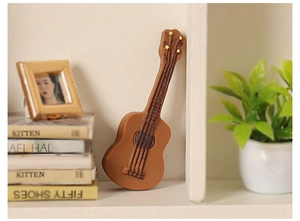 Vista macro detallada de una guitarra miniatura de resina en una estantería
