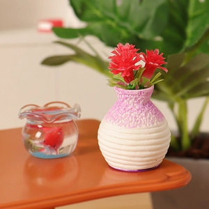 Miniature dollhouse set with a pink textured vase, red flowers, and small fish bowl