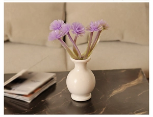 Detailed view of dollhouse miniature white ceramic vase with purple flowers for room decor