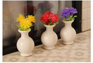 Detailed view of three miniature white vases with tiny yellow red and purple faux flowers
