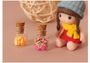 Miniature glass jars with cork stoppers filled with colorful simulated fruit slices decor