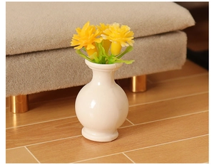 Macro shot of miniature white ceramic vase with yellow flowers for dollhouse decor