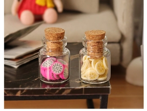 Miniature glass jars with cork stoppers containing tiny dragon fruit and lemon slices