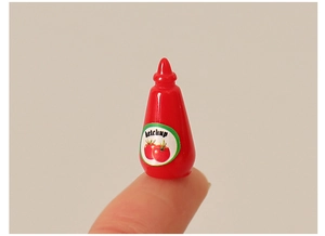 Miniature de bouteille de ketchup pour maison de poupée tenue sur un doigt