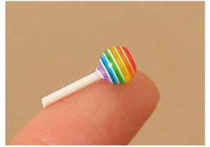 Primer plano de una piruleta arcoíris en miniatura en la punta del dedo para manualidades