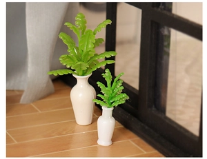 Close-up of two dollhouse miniature green plants in white vases on a wooden floor