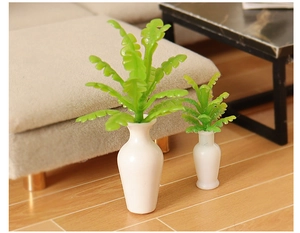 Miniature dollhouse decor with white ceramic vases and green ferns in a cozy living room scene