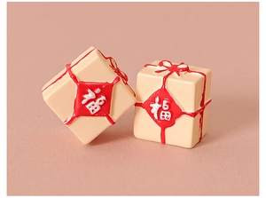 Gros plan de boîtes cadeaux miniatures beiges avec rubans rouges et caractère Fu chinois