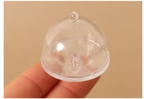 Close-up of a miniature clear food cover dome being held for dollhouse decoration