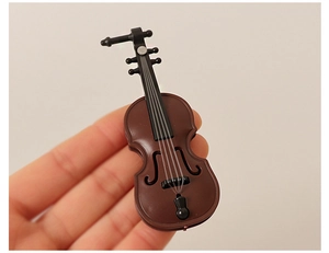Close-up of a miniature dollhouse cello model held in hand showing fine structural details