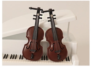 Detailed macro view of two miniature brown violin models leaning on a white toy piano