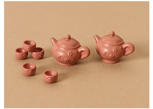 Detailed view of miniature 7-piece brown clay teapot set with embossed floral patterns