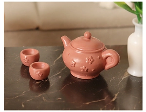 Macro shot of miniature dark pink tea set with 3D flower relief for dollhouse decor