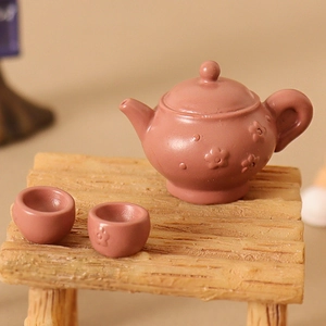 Miniature dollhouse tea set with embossed floral details on teapot and cups