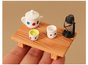 Miniature tea set with white polka dot teapot and lamp on a tiny wooden table