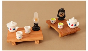Miniature dollhouse tea set with white dotted teapot and wooden table decor