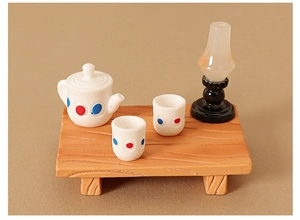 Macro view of miniature dollhouse tea set with oil lamp on orange wood table