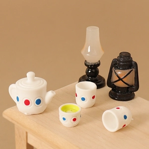 Miniature dollhouse tea set with white polka dot teapot and vintage lanterns on a wooden table