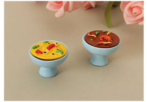 Detailed macro view of two miniature dollhouse hot pot models in blue ceramic style bowls
