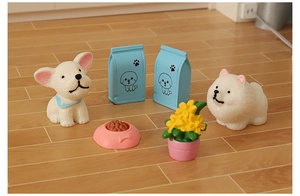 Miniature dollhouse pet scene with cartoon puppies, dog food bags, and a pink bowl