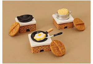 Macro shot of miniature dollhouse stove with vintage brick base and tiny cookware sets