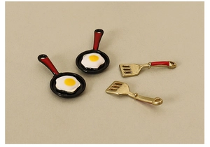 Detailed view of miniature frying pans and spatulas for dollhouse kitchen decor