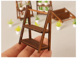 Close-up of a miniature two-tier dark brown wooden display shelf for dollhouse decor