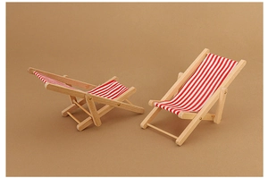 Close-up of dollhouse miniature beach chairs with red and white striped fabric and wood