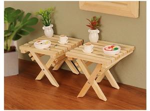 Detailed macro view of two miniature wooden folding tables with X-shaped frame and wood grain
