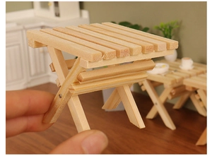 Close-up of a miniature wooden folding table with X-shaped legs for dollhouse decor