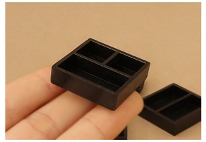 Nahaufnahme eines schwarzen Miniatur-Tabletts mit drei Fächern für das Puppenhaus