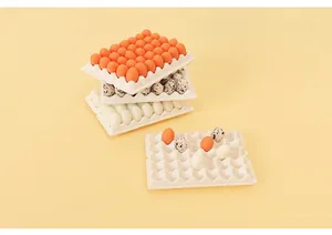 Close-up of miniature dollhouse egg trays with white, orange, and spotted resin eggs