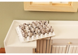 Detailed macro view of miniature dollhouse quail eggs with tray on a tiny white cabinet
