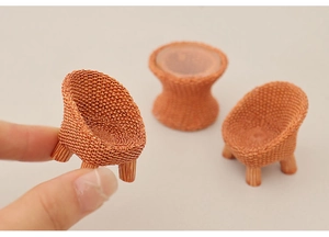 Close-up of a miniature dollhouse chair held by fingers to show micro scale size