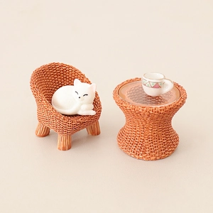 Miniature dollhouse furniture set with rattan chair, round table, and a tiny sleeping cat