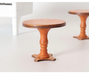Macro detail of miniature wooden round table showing natural grain and vintage carved leg