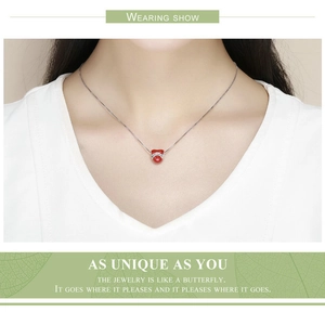 Gros plan d'un délicat collier en argent avec pendentif cœur rouge porté par un mannequin