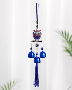 Detail of owl evil eye wind chime with blue metal bells and hanging tassels for home decor
